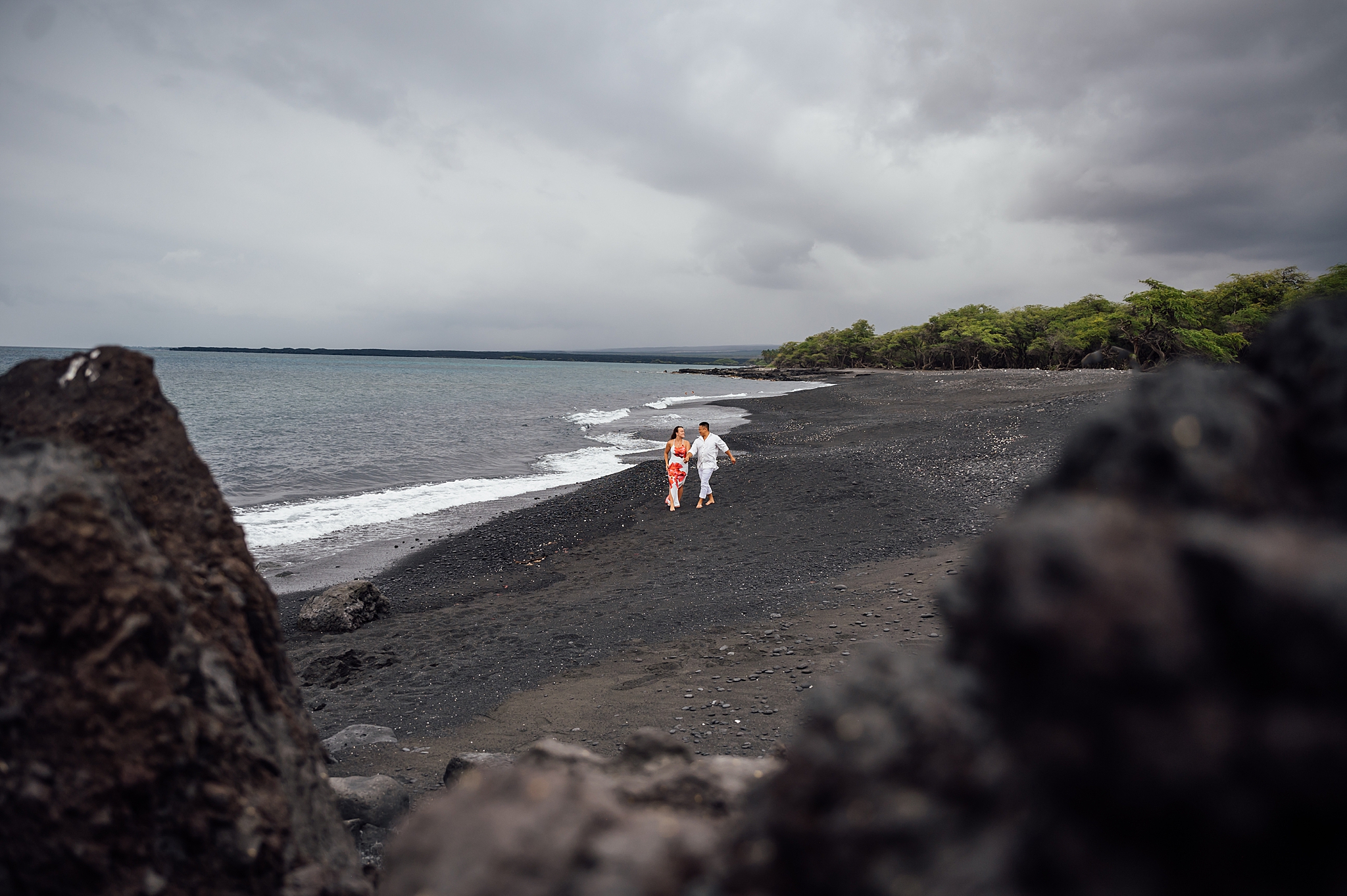 couple walking on a black sand beach in Hawaii
