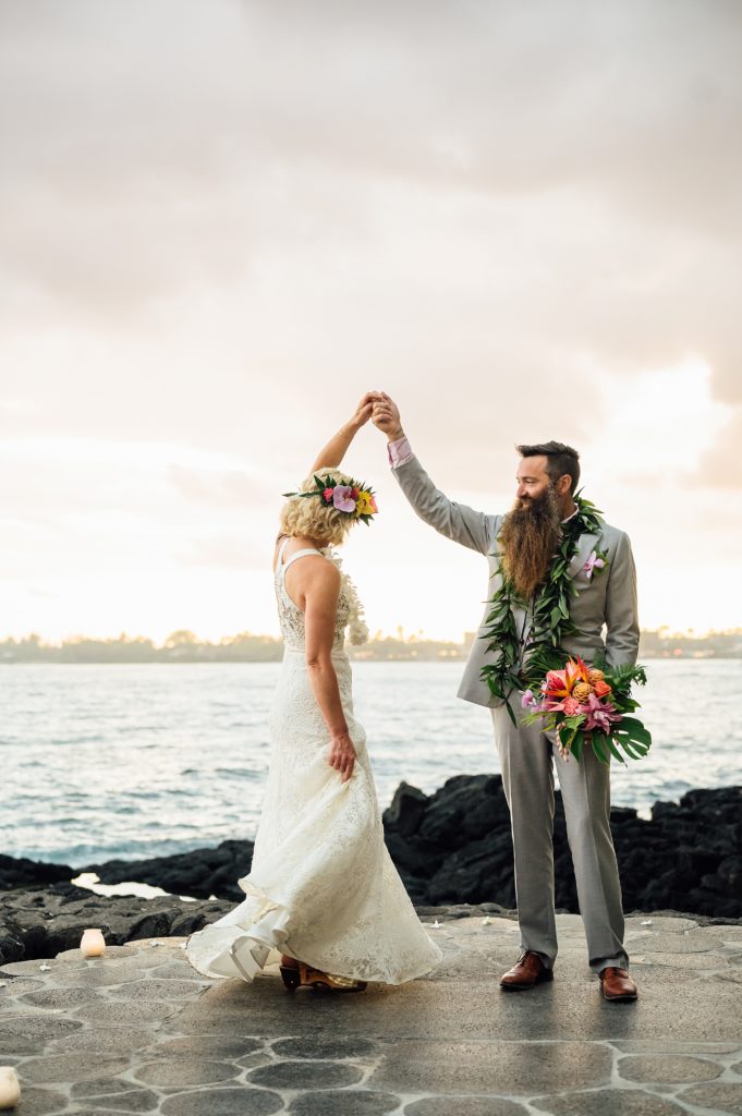 groom with bride twirling at a resort in Kona
