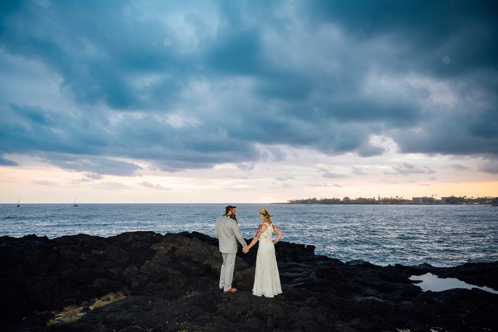 newlyweds holding hands on the lava rocks at Kona