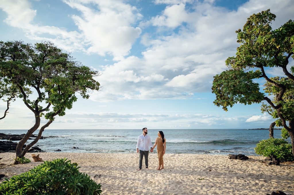 engagement photo of a couple holding hands at a beach 