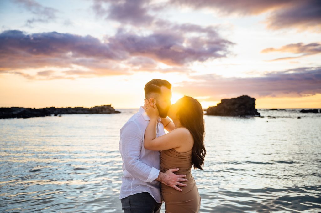 engagement photo of a couple kissing during sunset 