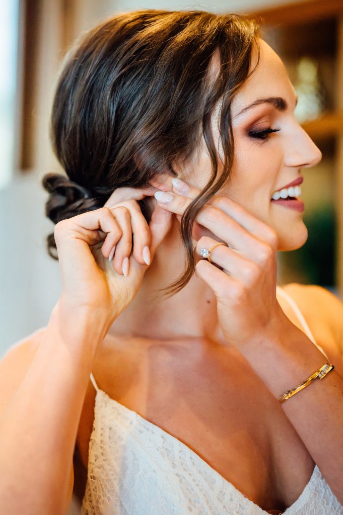 bride putting on her earrings by wedding photographer