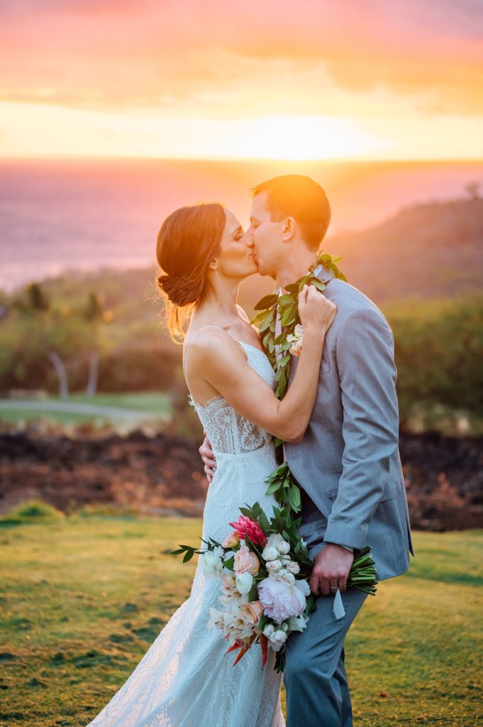 newlyweds kissing under the radiant sunset in Hawaii 