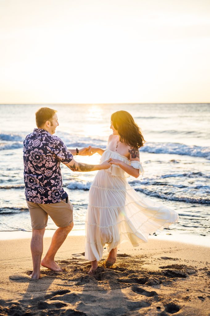 couple dancing happily at Kukio beach during sunset