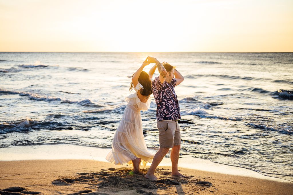 couple dancing happily at Kukio beach during sunset