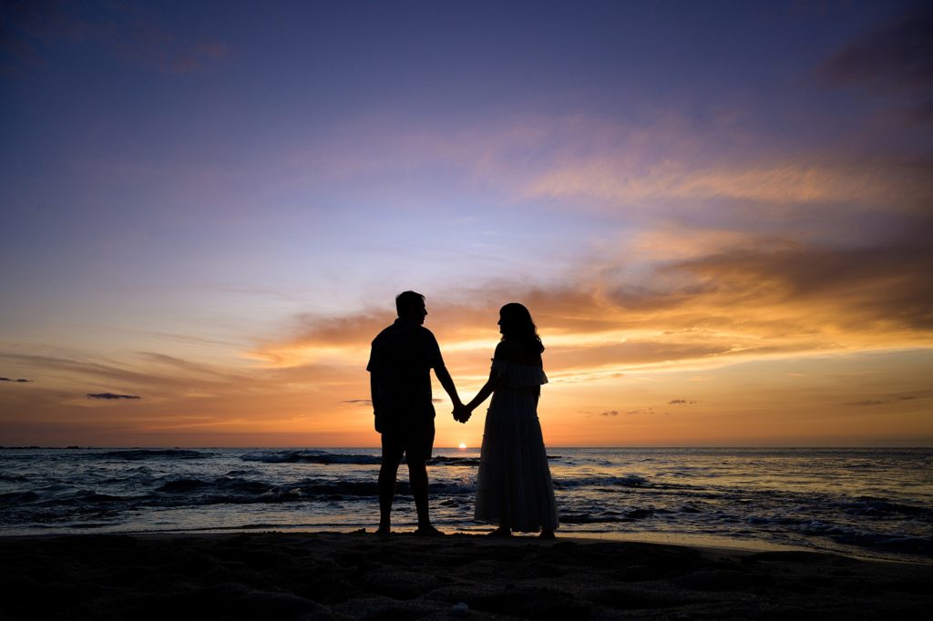couple holding hands during sunset by Hawaii photographer at Kukio