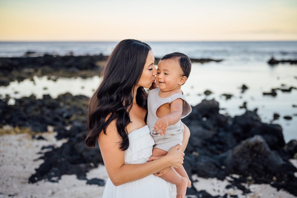 photo of mom kissing her baby's cheeks at Hawaii beach
