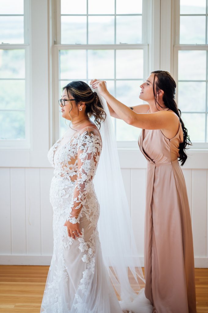 bridesmaid putting on the wedding veil to the bride 