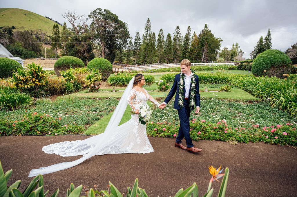 bride and groom holding hands at a garden in Big Island