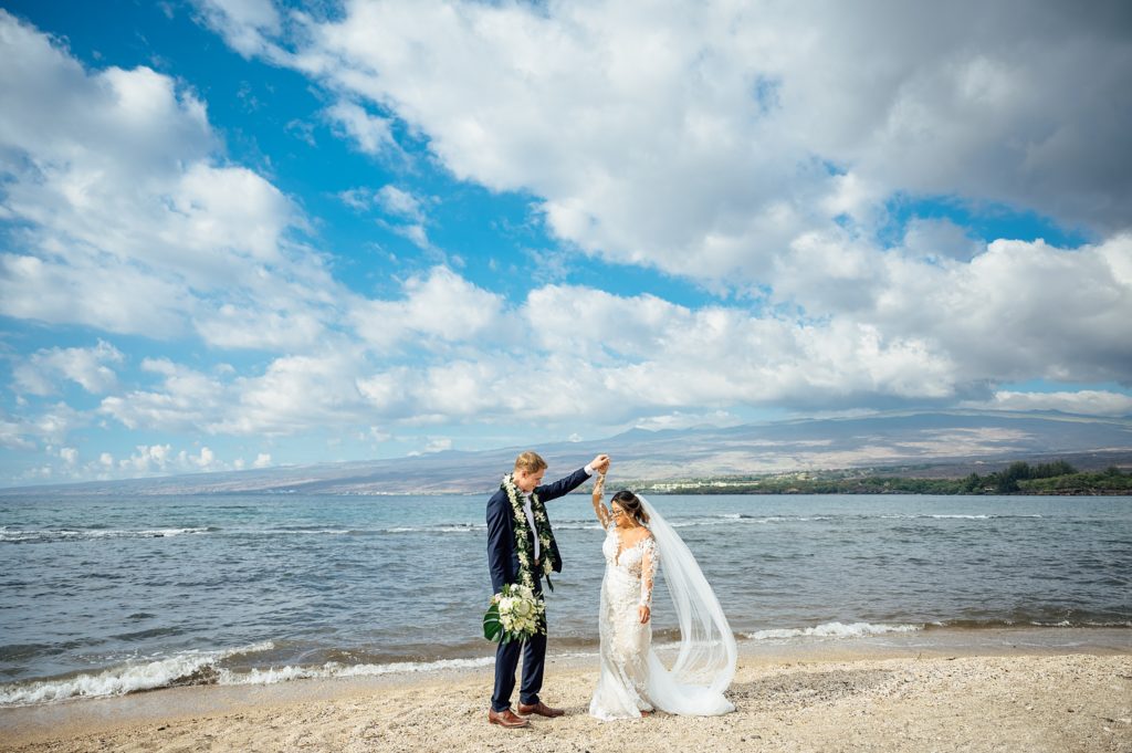 groom with the bride twirling at Puako beach in Hawaii