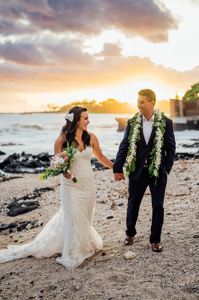 bride and groom holding hands during sunset at Hawaii beach