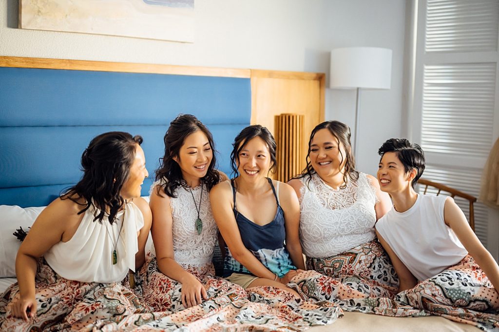 bride with bridesmaids sitting on the bed