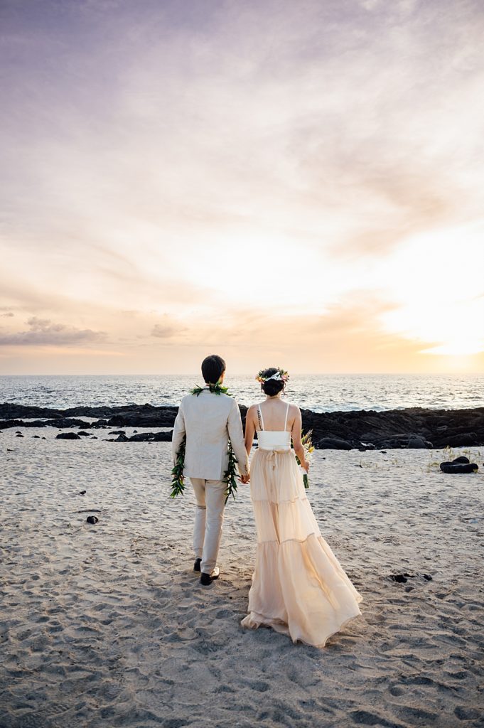 bride and groom walking towards the shore in Kona