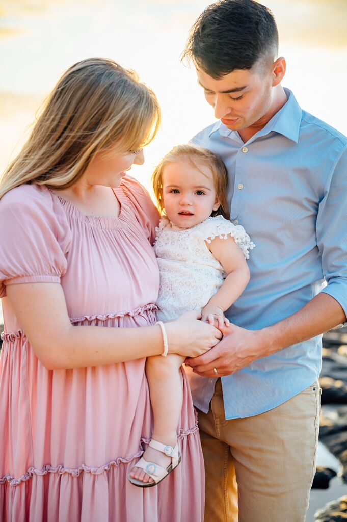 parents looking at their baby girl by beach photographer
