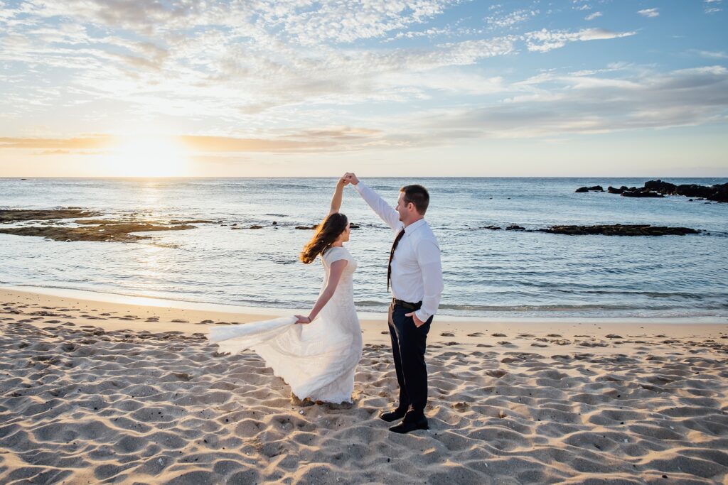 bride with groom twirling on a white sand beach